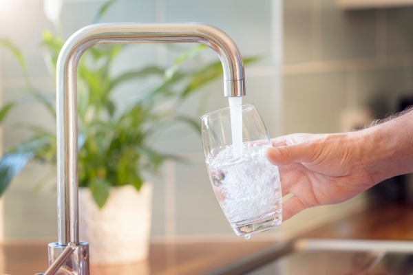 Wasser aus dem Hahn fließt in ein Glas